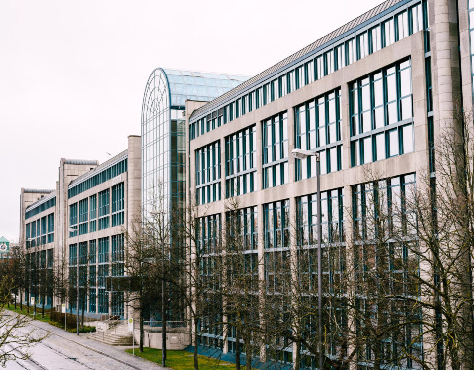 Budynek handlowy z szklanymi oknami w zimowej scenerii, przedstawiający architekturę miejską.