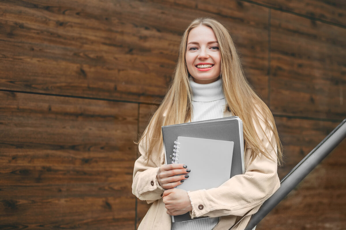 Kobieta uśmiechnięta trzymająca laptopa, korzystająca z komputera w poszukiwaniu pracy.